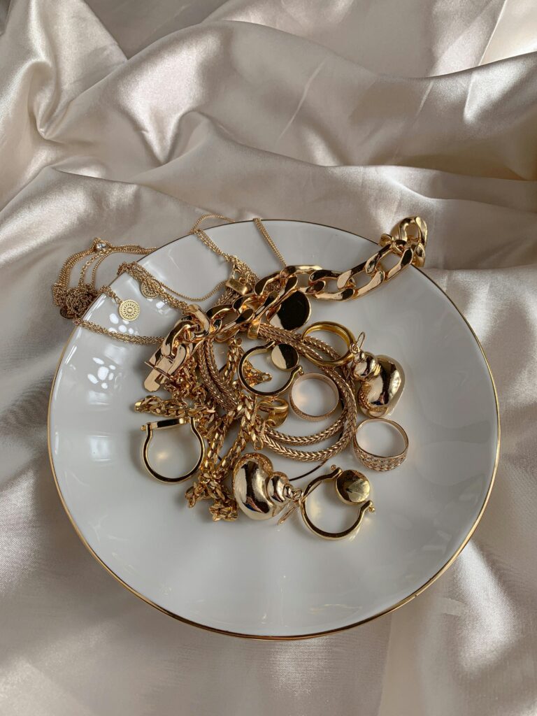 Stylish gold rings and necklaces elegantly displayed on a saucer with a silk background.